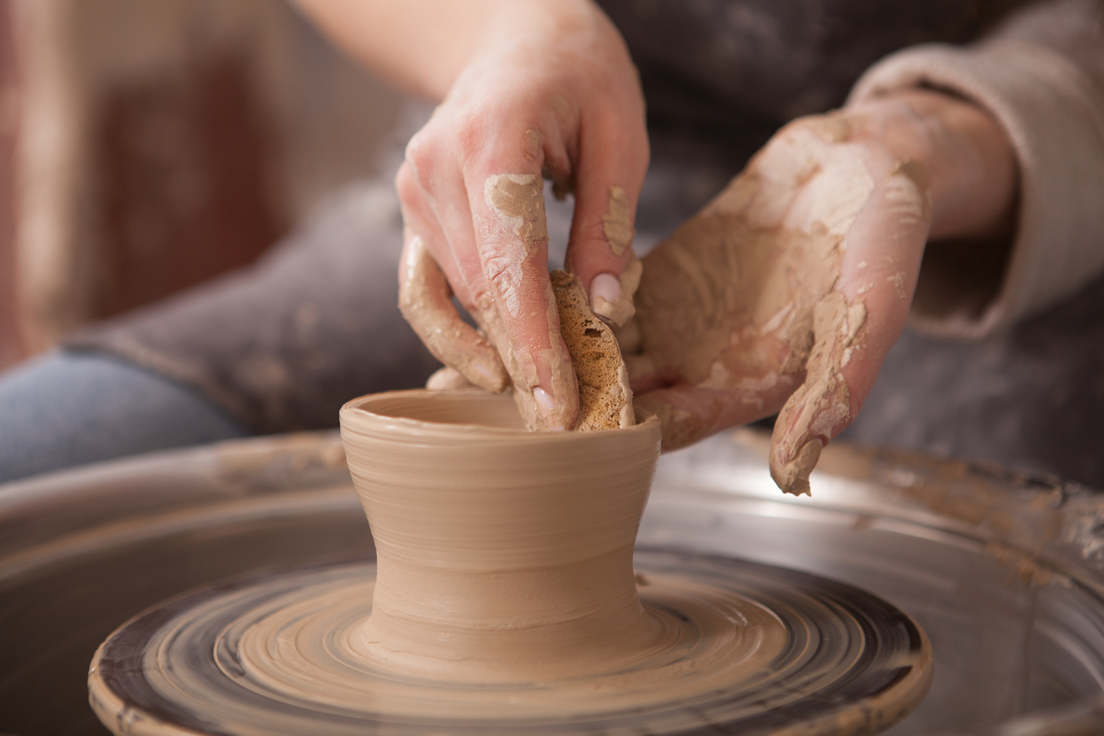 Woman throwing pots on potters wheel